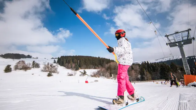 jeune skieuse remontant une piste en téléski à Prabouré avec forêt en arrière-plan