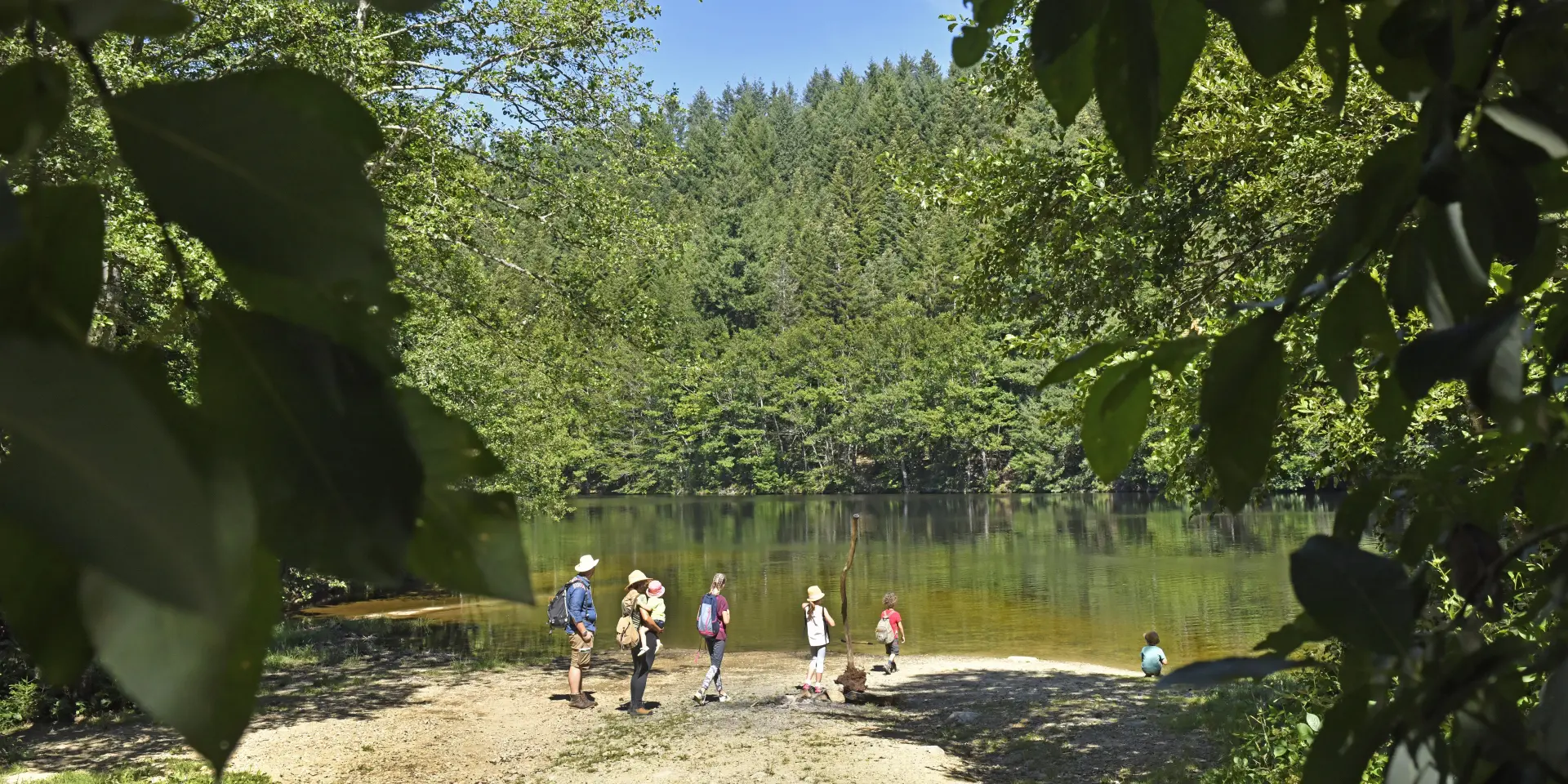 Une famille observe la retenue d’eau du barrage de la Muratte depuis une plage naturelle à Palladuc.