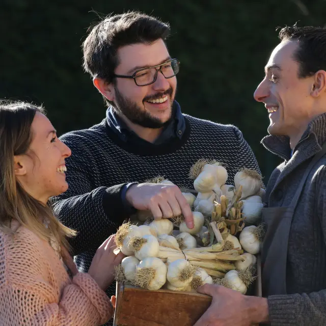 Couple discutant avec un producteur d’ail rose de Billom devant une caisse en bois.