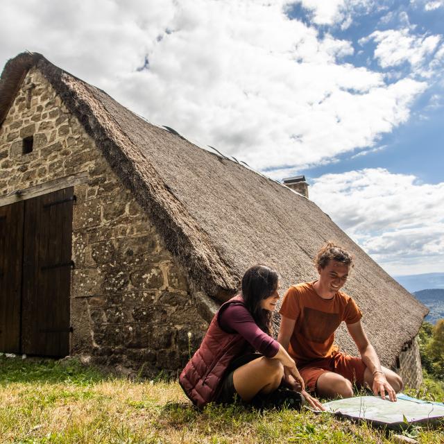 Couple devant une jasserie sur les Hautes Chaumes, consultant une carte.