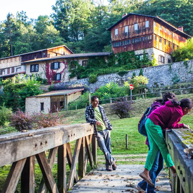 Famille sur un pont devant le Moulin Richard de Bas, entouré de nature.