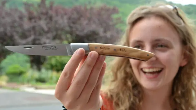 Une visiteuse présente le couteau qu'elle a fabriqué lors d'un atelier de montage.