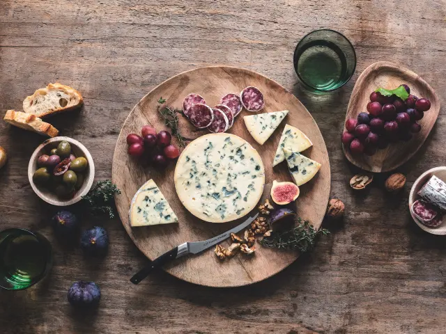 Fourme d'Ambert sur planche avec pain, raisin, saucisson, figues, olives et noix.