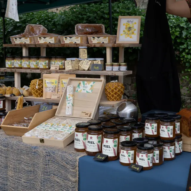 Stand de miel avec pots, nougat, pain d’épices et bougies artisanales sur un marché en Auvergne