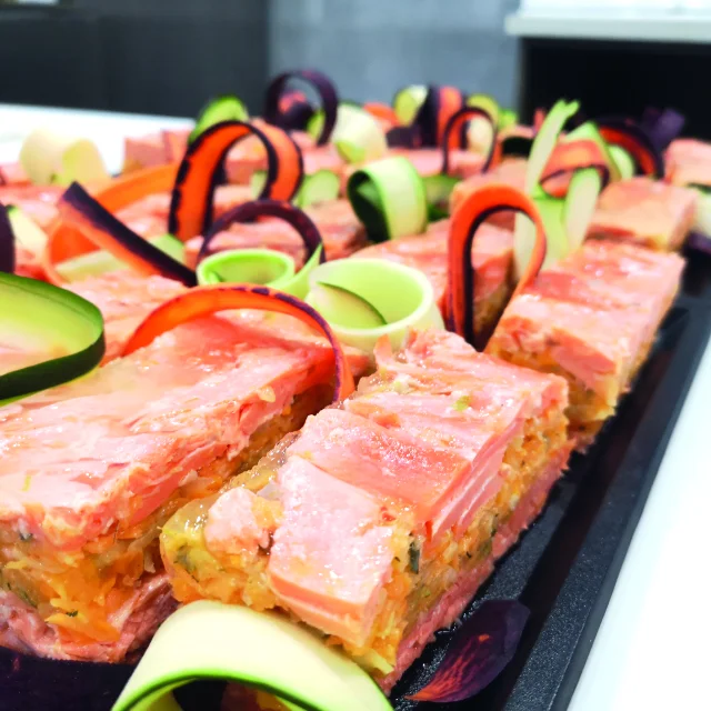 errines de truite alignées, décorées avec des juliennes de légumes colorées.