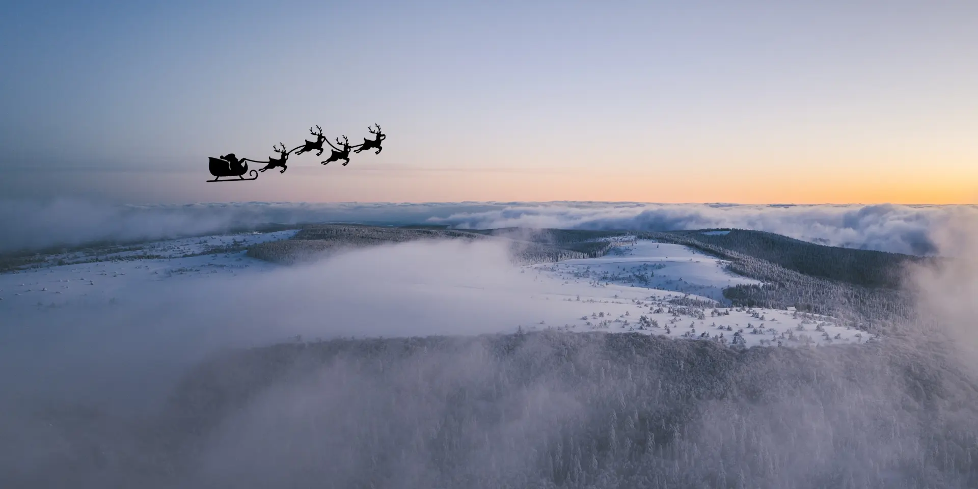 Le Père Noël survole un paysage enneigé du Livradois-Forez vu depuis les airs.